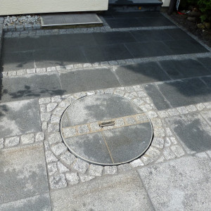 Helmes Gartenbau - Lichtschacht und Kanaldeckel